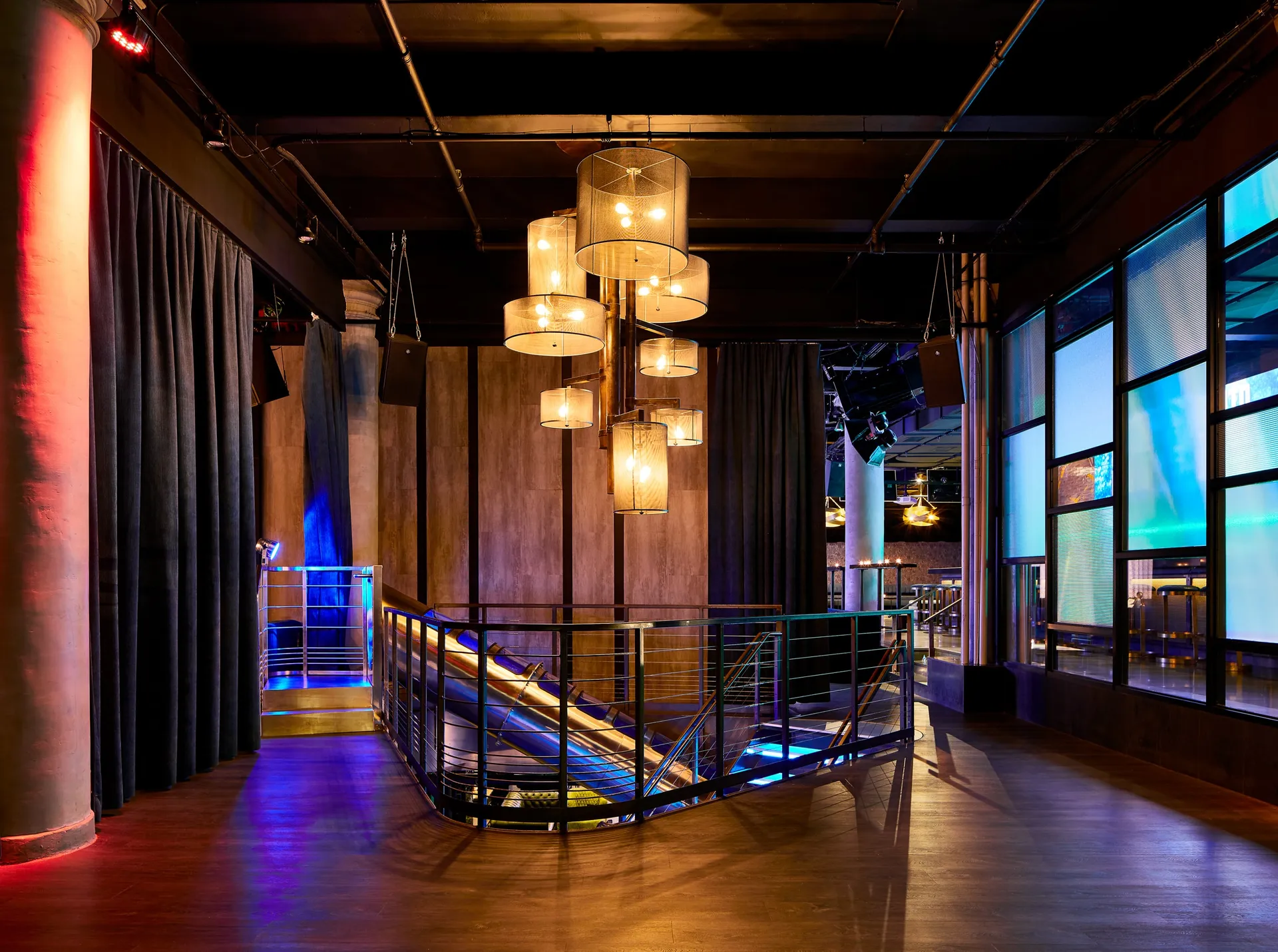 Slate NYC mezzanine with hanging amber lights and a stair rail